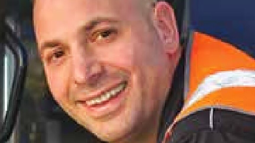 Paul Virgona is dressed in a high-visibility orange vest as he smiles at the camera.
