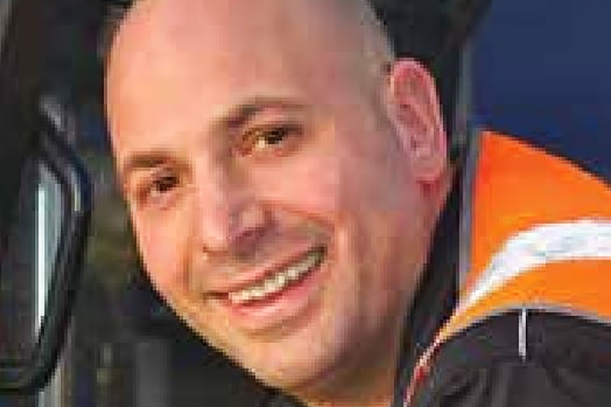 Paul Virgona is dressed in a high-visibility orange vest as he smiles at the camera.