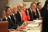 Turnbull is looking towards camera smiling, while his colleagues either side of him are not looking towards camera.