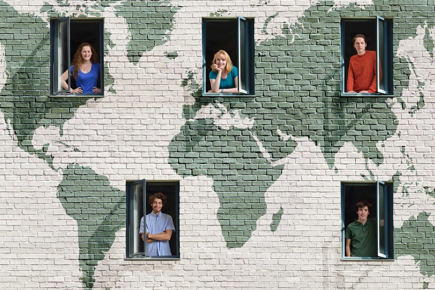 People in windows in a wall with a world map