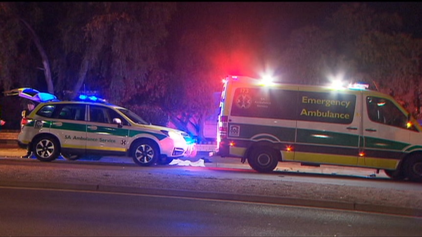 Two ambulances parked on the side of a road with lights flashing