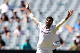 Jasprit Bumrah smiles with both hands raised above his head