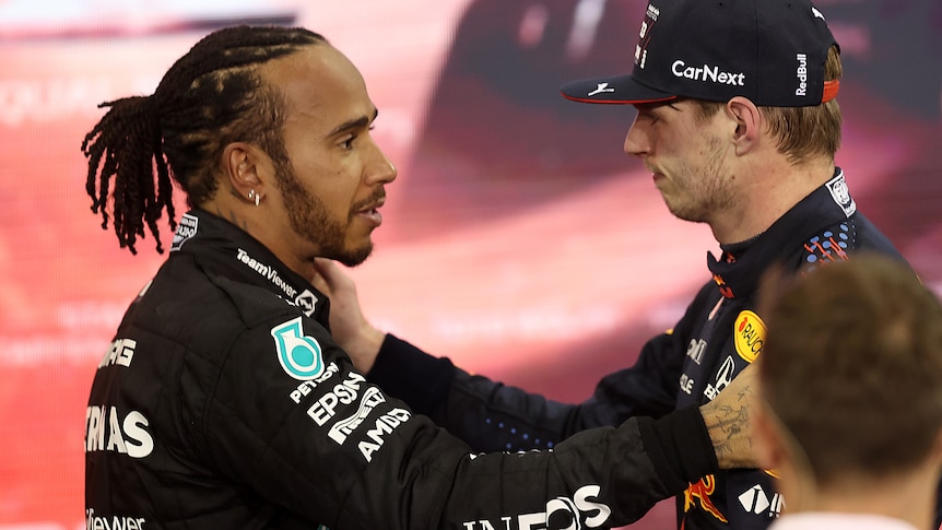 Two race drivers embrace after a hard fought race.