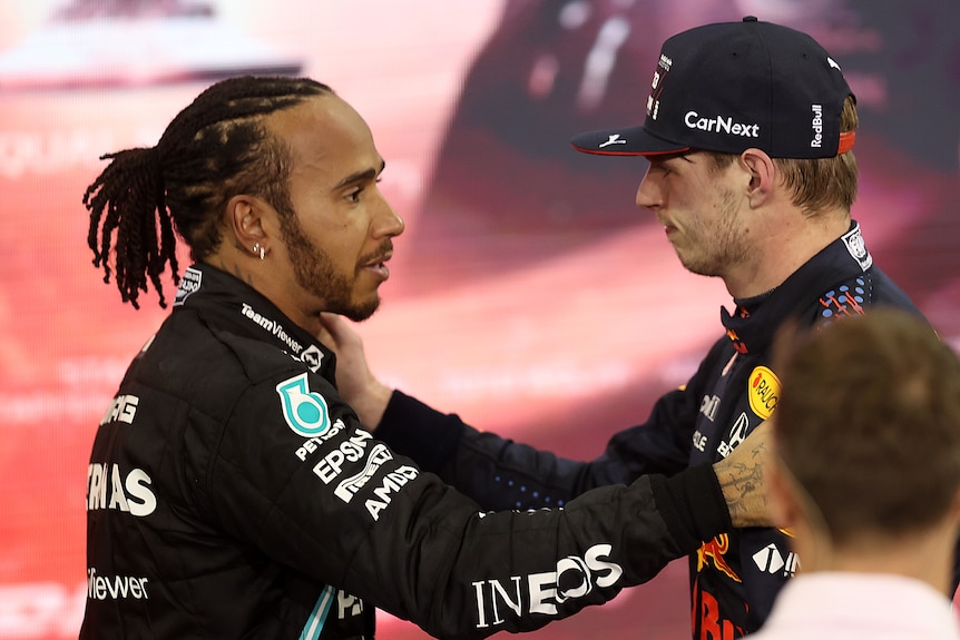 Two race drivers embrace after a hard fought race.