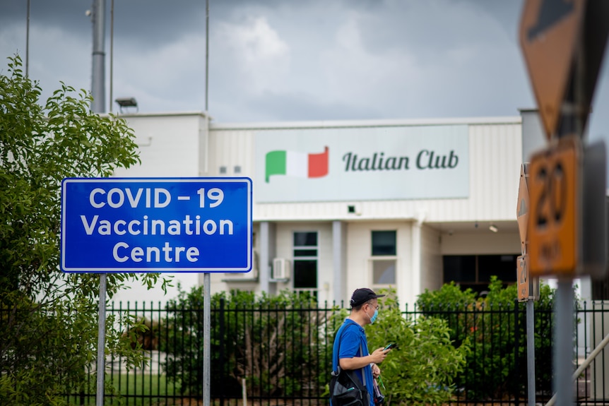Un homme marche près d'une clôture devant le centre de vaccination COVID-19 du club italien de Marrara.