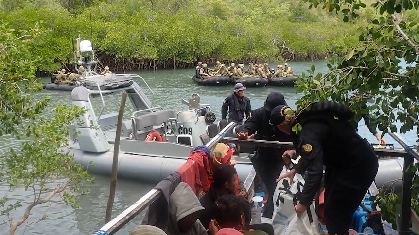 Australian Border Force boat pins a fishing boat against mangroves.
