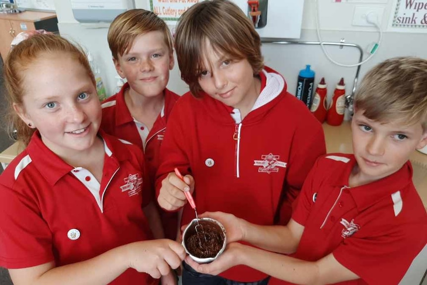 Four primary-school students dressed in red polo uniforms show off their chocolate concoction.
