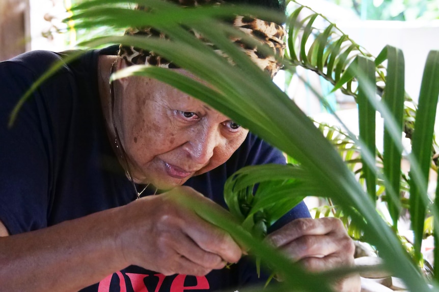 close up of woman weaving coconut leaves