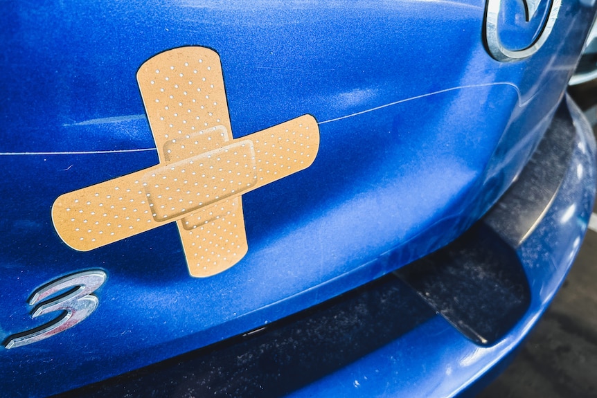 two 'bandaid' stickers on a car body covering a dent