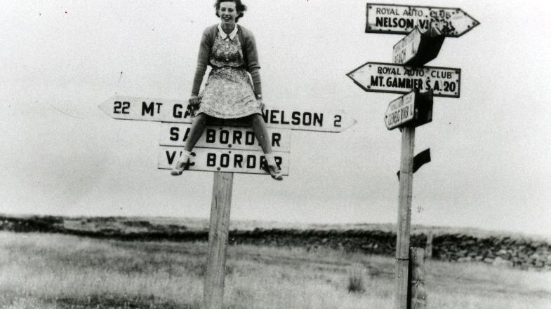 Girl sitting on SA/VIC border sign