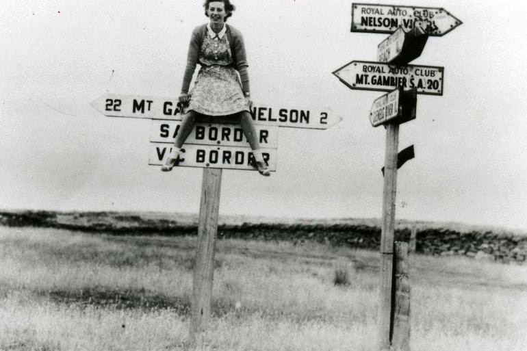Girl sitting on SA/VIC border sign