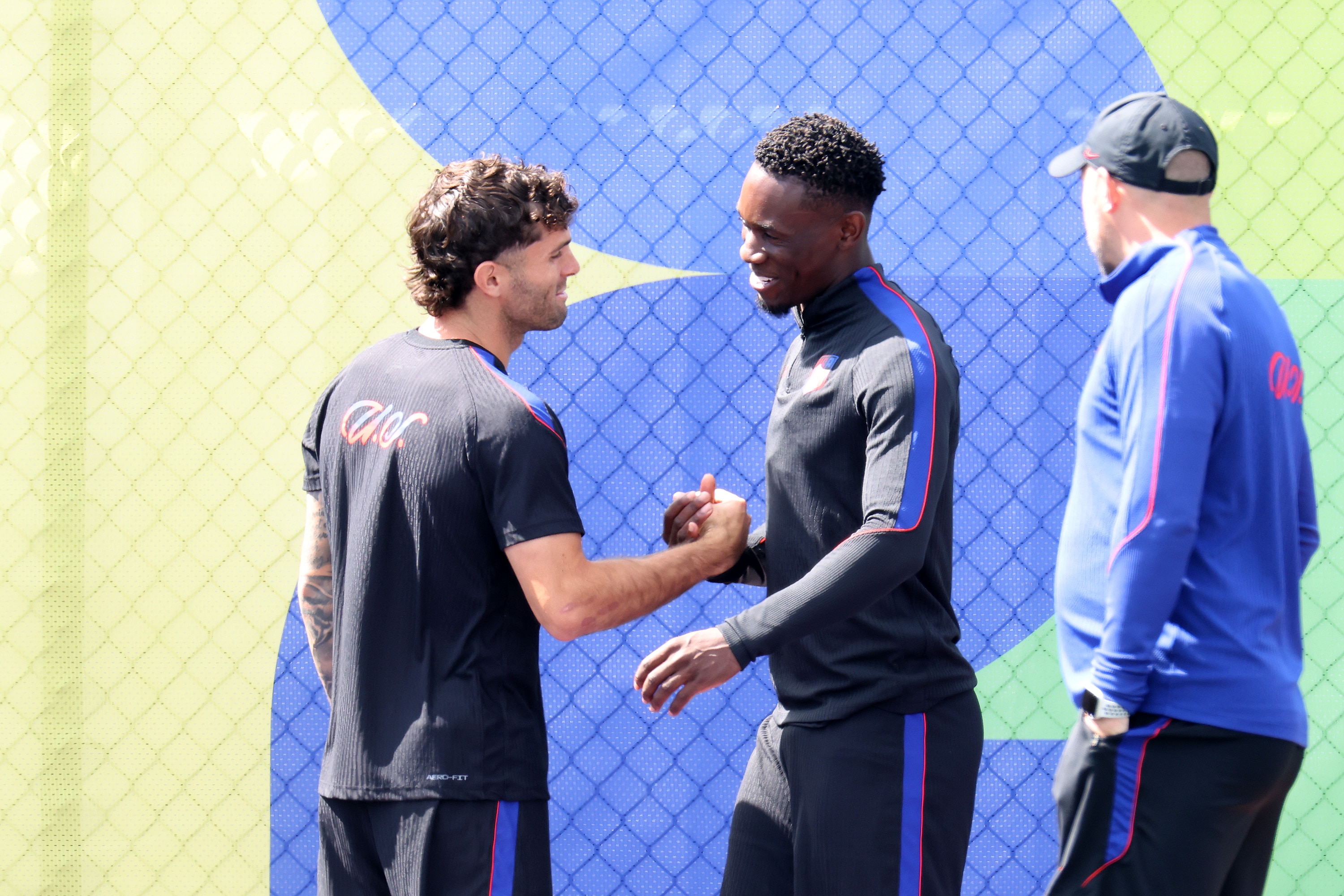 USA players Christian Pulisic and Folarin Balogun bring their hands together and smile during training