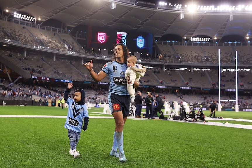NSW Blues' Jarome Luai walks around Perth Stadium with two children. One walking and one carried.