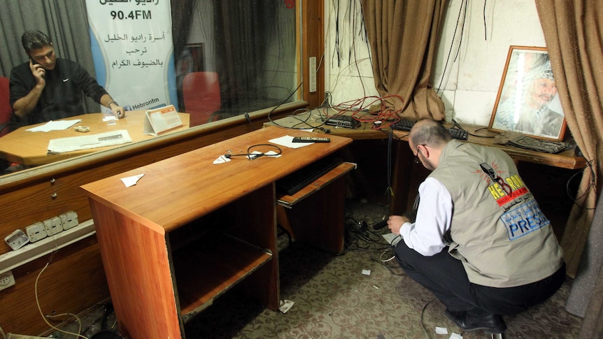 Palestinia journalists check the damage after Israeli soldiers entered the offices of the local Palestinian Al-Khalil radio