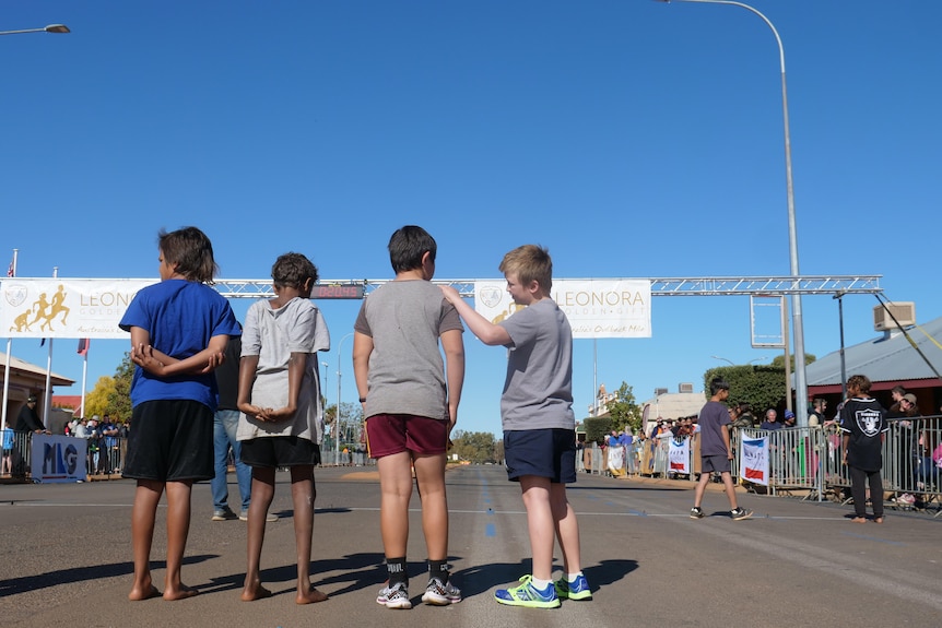 four boys with their backs to the camera talking to one another