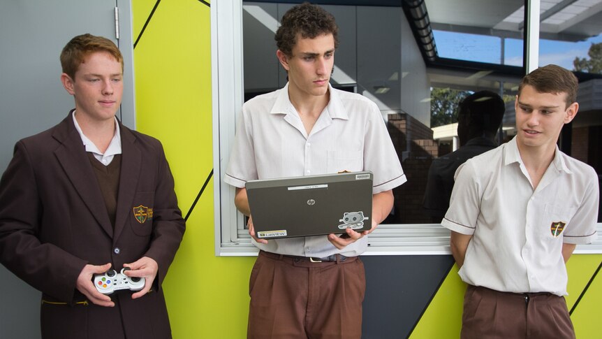 Students use both a control and a laptop to control the robot.