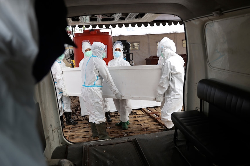 Health workers carry a coffin containing the body of a COVID-19 victim into an ambulance