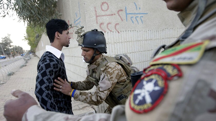 Iraqi soldier frisks Iraqi man at Baghdad polling centre