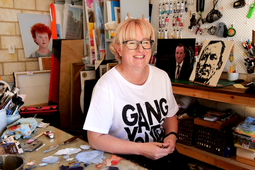 A woman sitting in a painting studio.