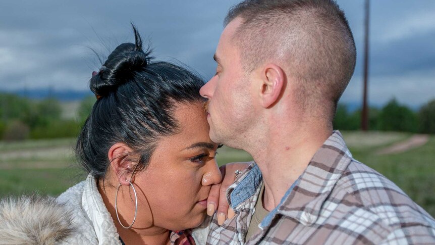 A man kisses a woman's forehead