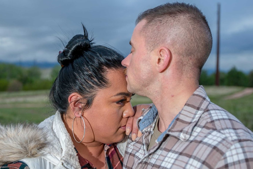 A man kisses a woman's forehead