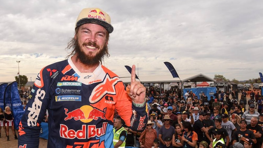 Toby Price holds up a finger denoting first place at the finishing line.