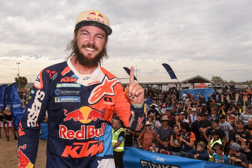 Toby Price holds up a finger denoting first place at the finishing line.