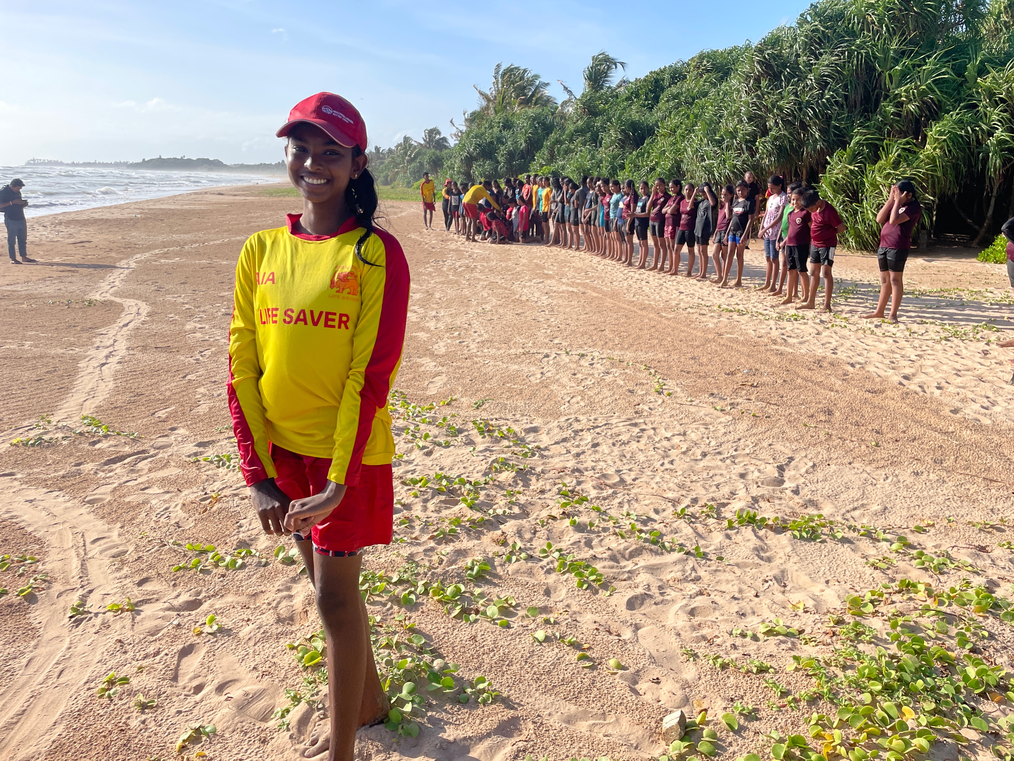 Uma jovem veste uma camisa vermelha e amarela na praia.