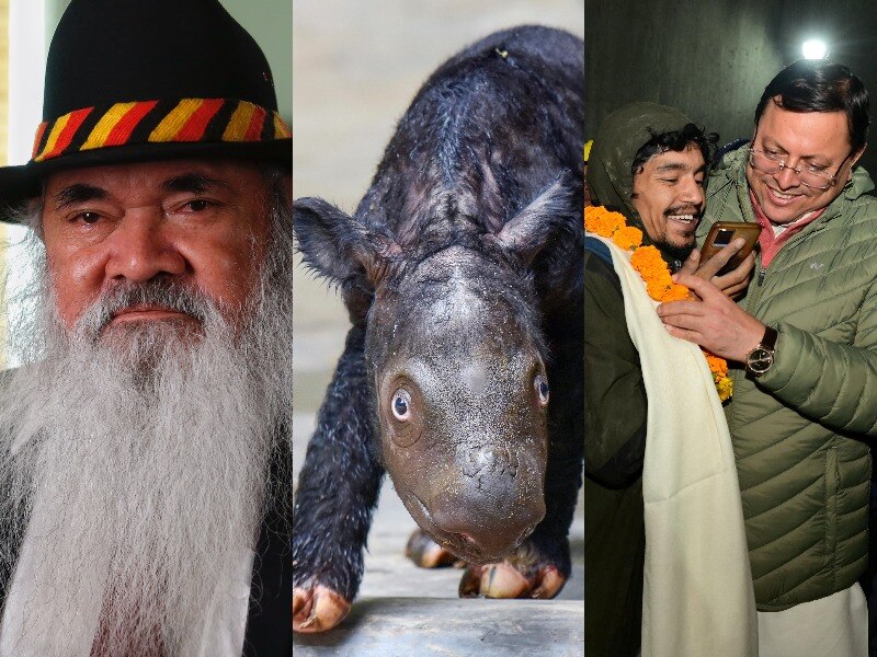 Senator Pat Dodson, a rhino calf and two men smiling. 