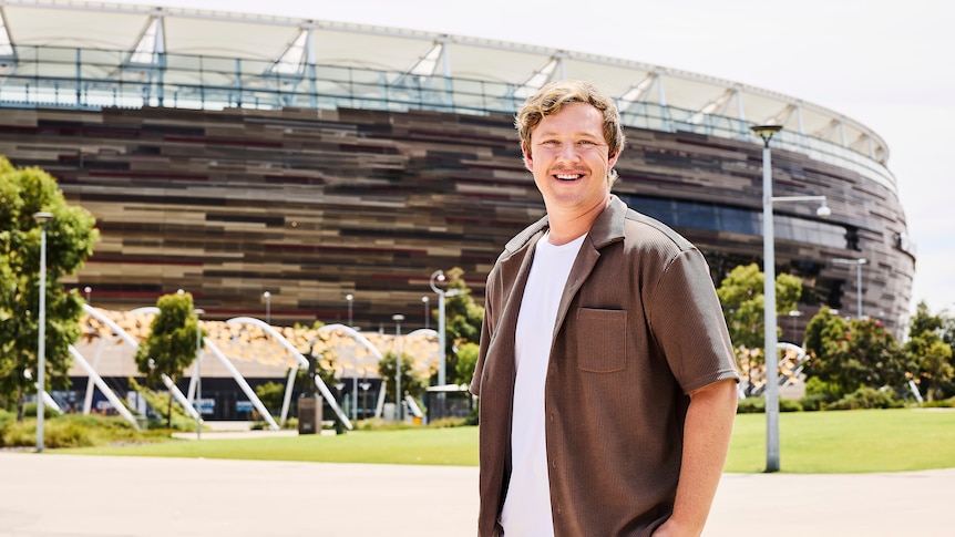 Mitch Turner standing outside Optus Stadium in Perth on a bright sunny day.