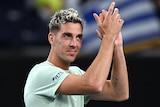 An Australian male professional tennis player claps his hands after winning a match at the Australian Open.