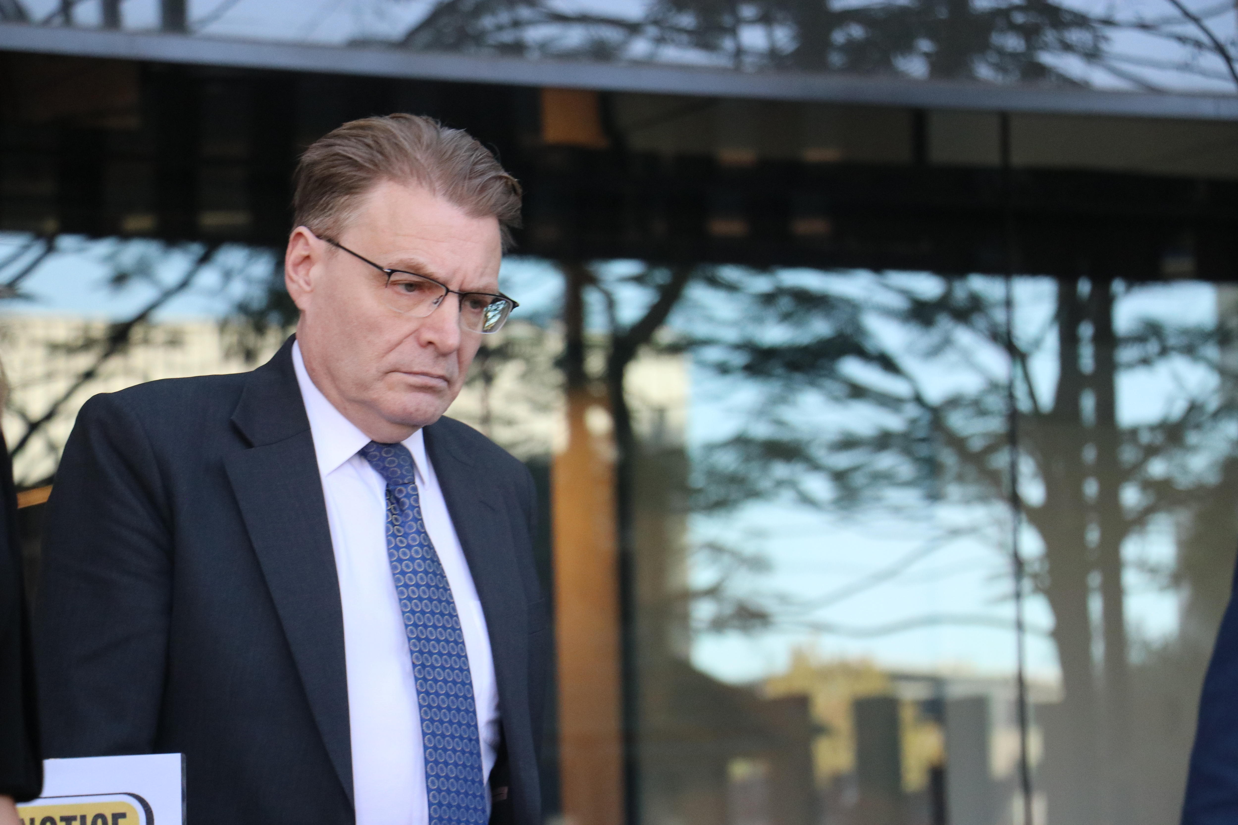 A man in a suit looks serious while walking.