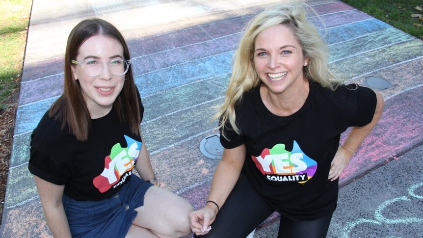 Two women wearing yes shirts sit with campaign material in Alfred Park