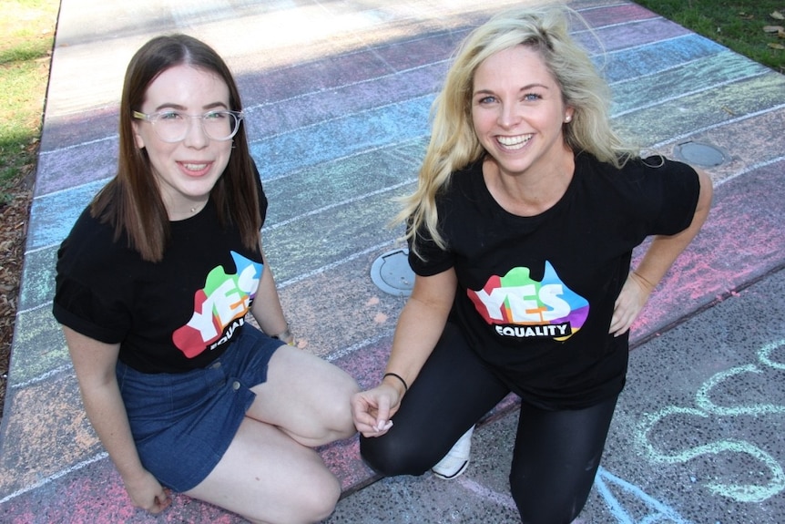 Two women wearing yes shirts sit with campaign material in Alfred Park