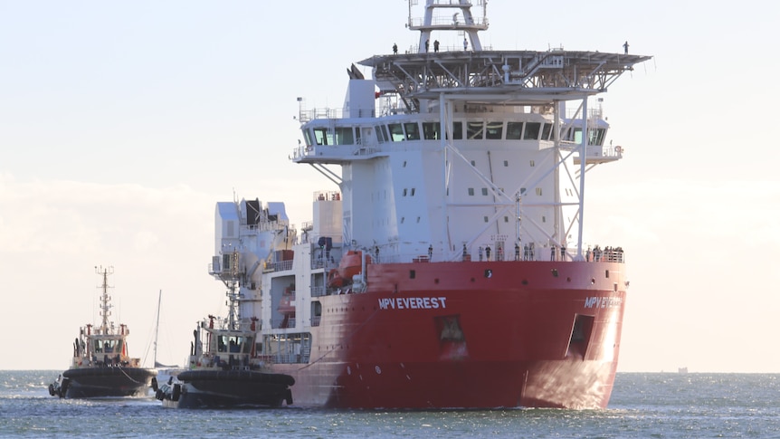 A large ship flanked by two smaller ships on the sea.