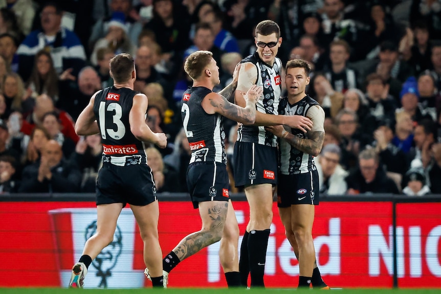 Collingwood players gather round Mason Cox to congratulate him