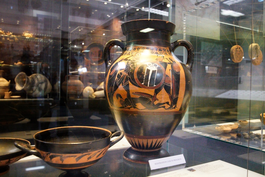An ancient Mediterranian amphora in a glass display case.