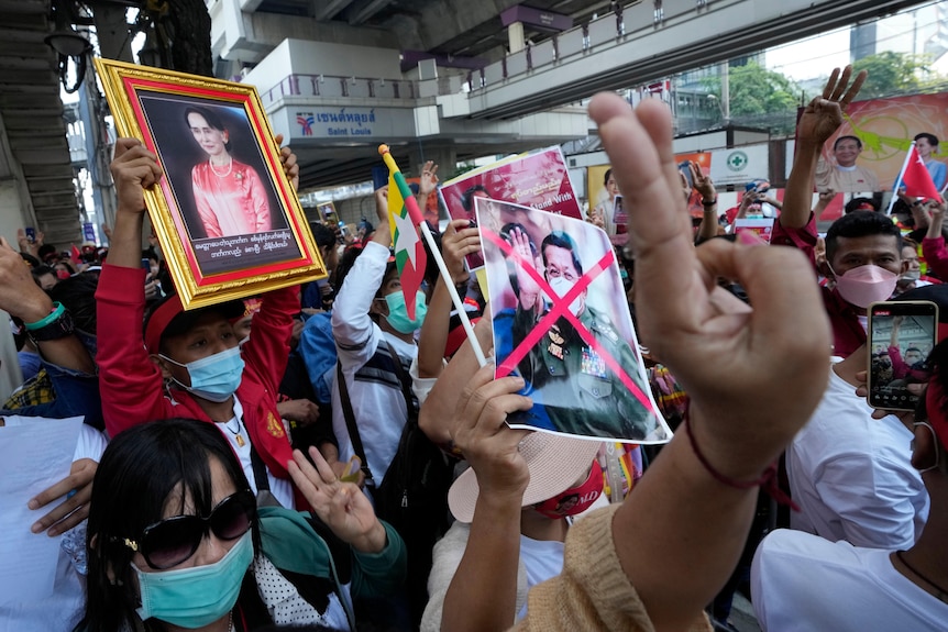 Protesters hold signs and banners as they march, some holding their middle three fingers aloft.