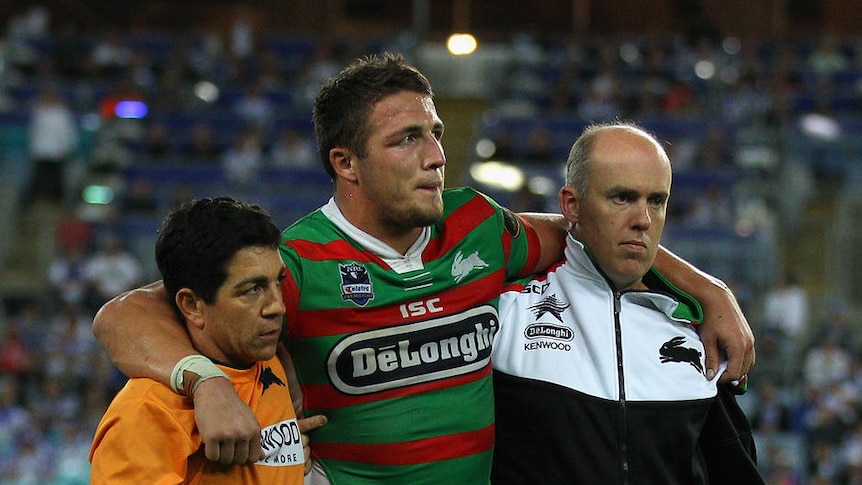 More injury woes... Sam Burgess is escorted from the field in another black night for the Rabbitohs.