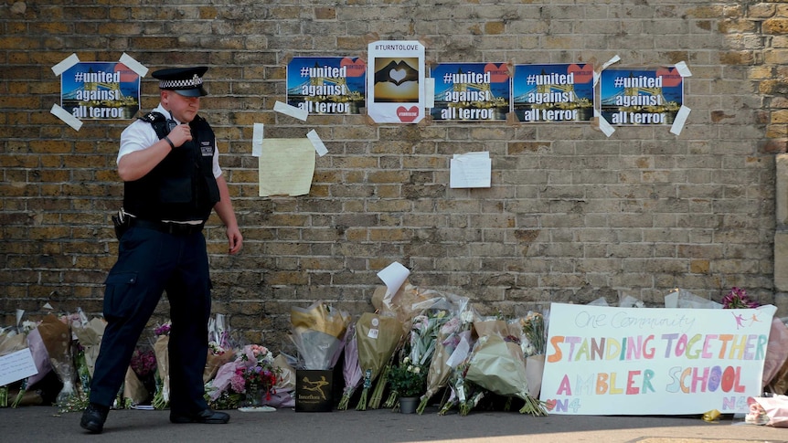 A policeman stands near floral tributes left after an attack near a London mosque.