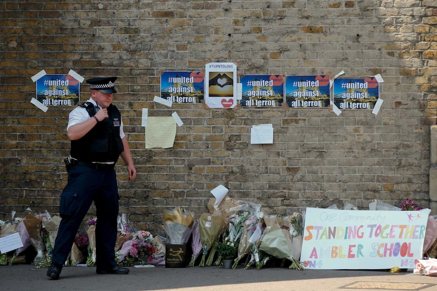 A policeman stands near floral tributes left after an attack near a London mosque.