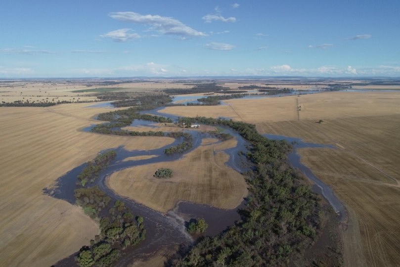 An aerial view of a flooded river snaking through brown land.