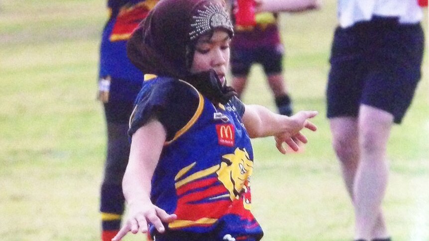 10-year-old Afghani refugee Zimra Hussain kicking an AFL football in Toowoomba on Queensland's Darling Downs