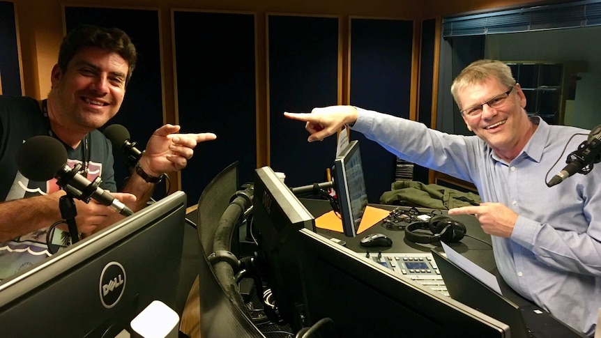 Russell Torrance and Martin Buzacott in a radio studio behind radio desks wearing headphones.