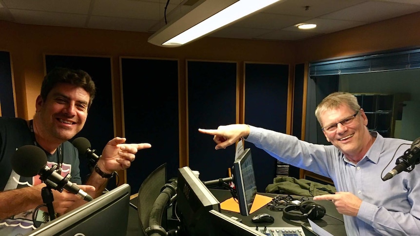 Russell Torrance and Martin Buzacott in a radio studio behind radio desks wearing headphones.