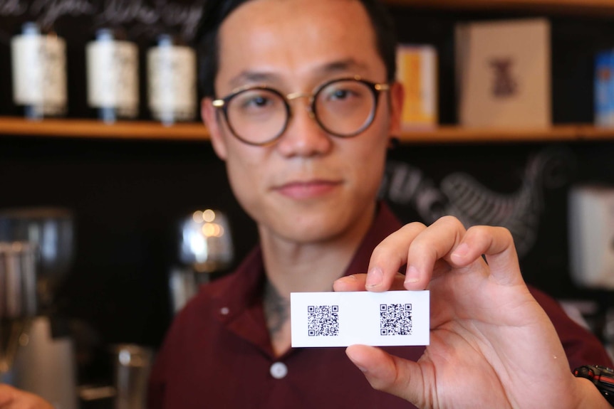 Cafe owner Ben Kim holds a card showing the address to his digital wallet