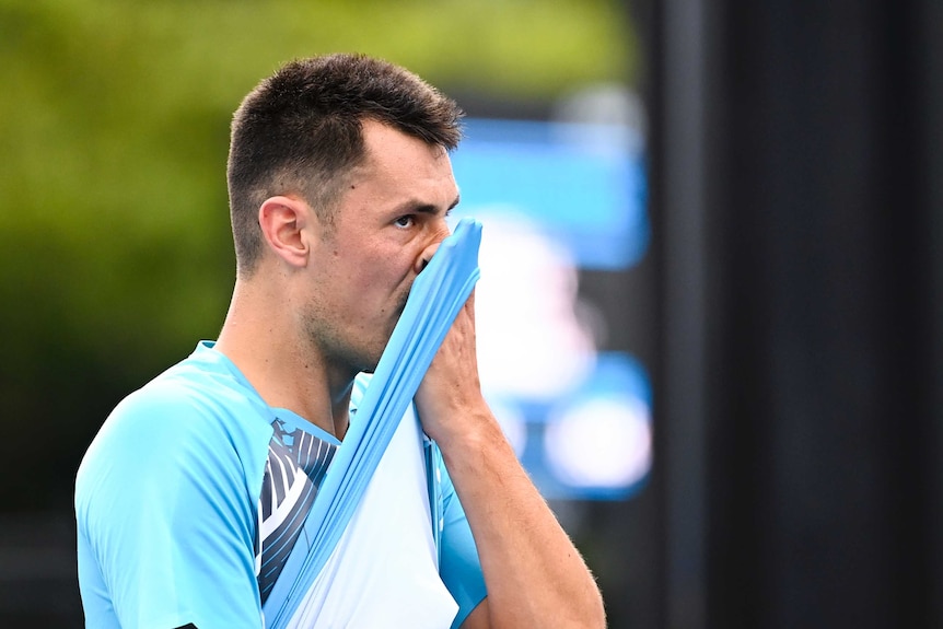 Bernard Tomic wipes his face with his shirt