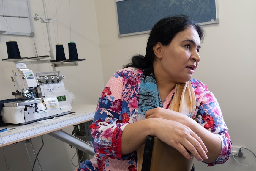 Farishta leans over the back of her chair to talk to someone. 