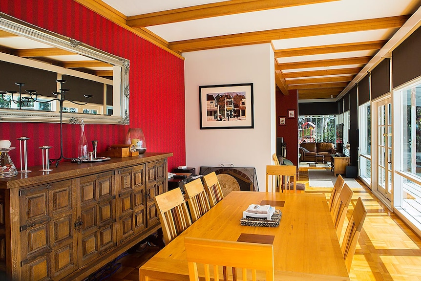 Interior of a home with large dining table, lined with windows on one side.