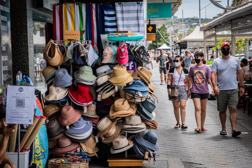 Three people walking next to a hat stand